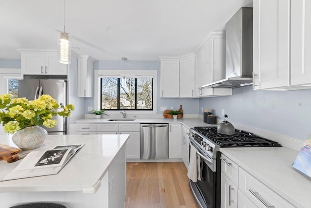 kitchen featuring white cabinetry, wall chimney exhaust hood, appliances with stainless steel finishes, and light countertops