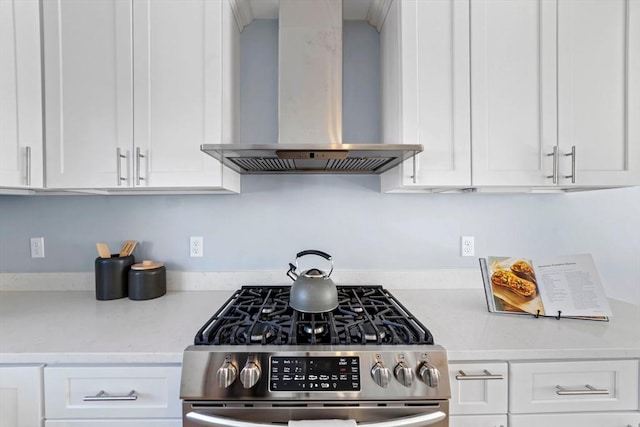 kitchen with white cabinets, stainless steel gas range, ventilation hood, and light countertops