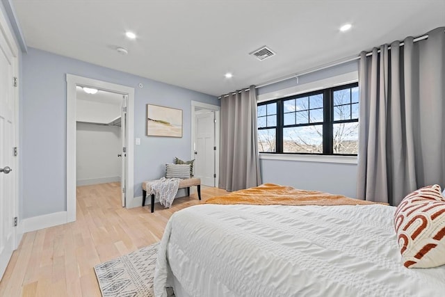 bedroom featuring a walk in closet, recessed lighting, visible vents, light wood-style floors, and baseboards