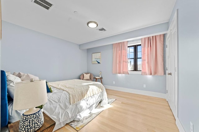 bedroom featuring visible vents, baseboards, and wood finished floors