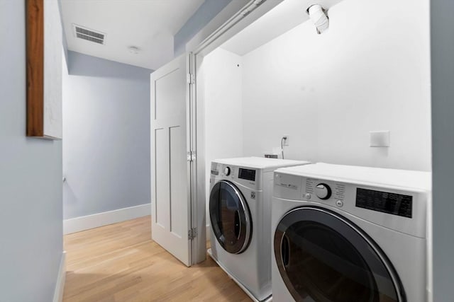 washroom featuring laundry area, visible vents, baseboards, washer and dryer, and light wood-type flooring