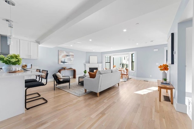 living area with recessed lighting, baseboards, a fireplace, and light wood finished floors