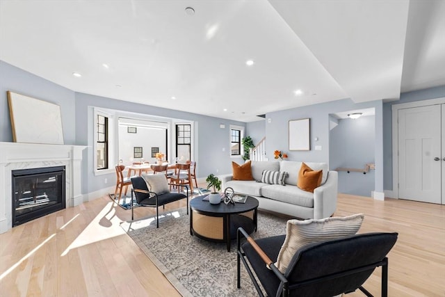 living room featuring baseboards, stairway, light wood-style floors, a fireplace, and recessed lighting