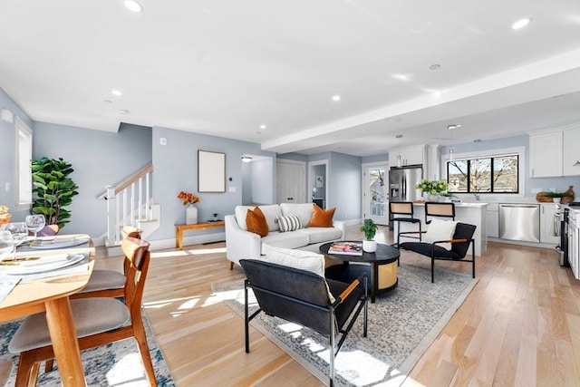 living room with light wood-style floors, baseboards, stairway, and recessed lighting