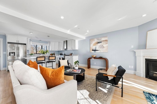 living room with light wood-style floors, a fireplace, baseboards, and recessed lighting