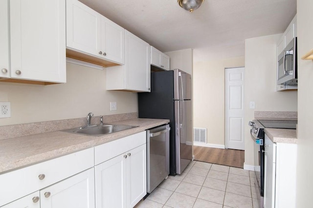 150 Elm St Unit 1, Braintree, MA 02184 - kitchen featuring stainless steel appliances, white cabinets, light tile patterned flooring, and light countertops