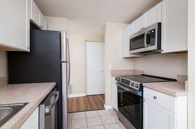150 Elm St Unit 1, Braintree, MA 02184 - kitchen with stainless steel appliances, light tile patterned flooring, white cabinetry, and light countertops