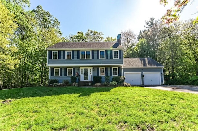 colonial inspired home featuring driveway, a garage, a chimney, and a front yard