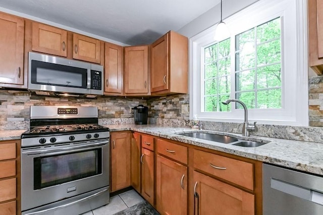 kitchen featuring appliances with stainless steel finishes, a sink, brown cabinetry, and backsplash