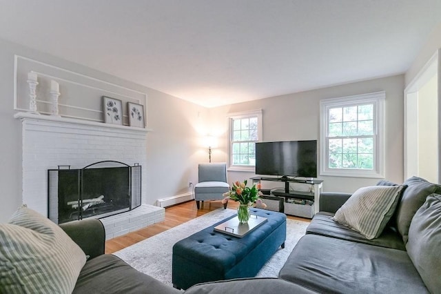 living room featuring wood finished floors, baseboard heating, and a fireplace