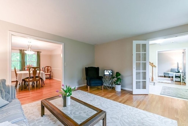 living area featuring wood finished floors, french doors, and baseboards