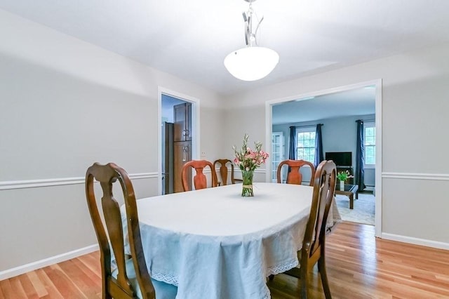 dining space with light wood finished floors and baseboards