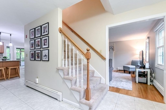 stairs featuring baseboard heating, tile patterned flooring, and baseboards