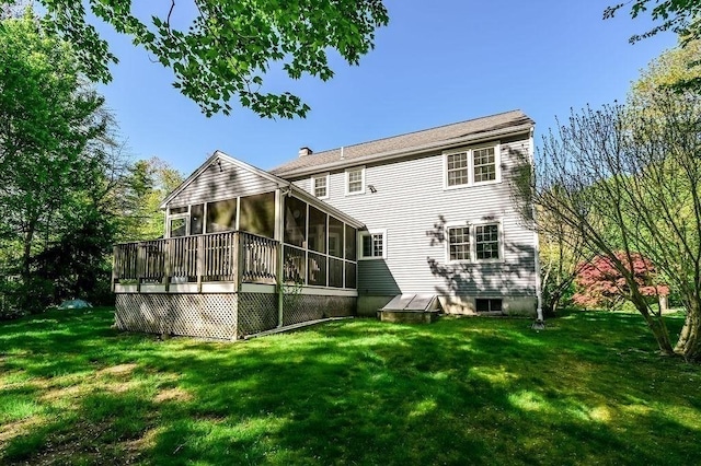 rear view of house with a sunroom, a yard, and a chimney