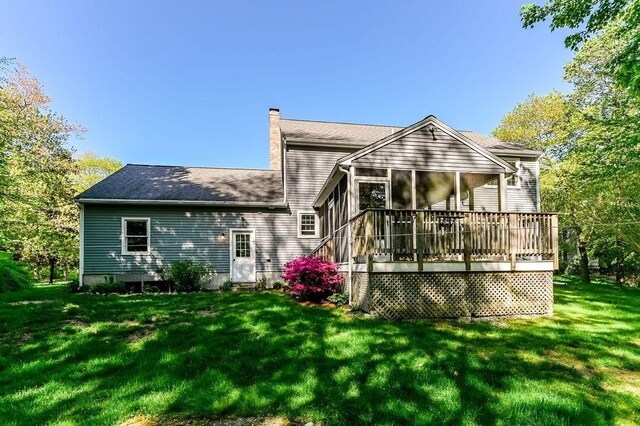 rear view of house with a chimney, a sunroom, and a yard