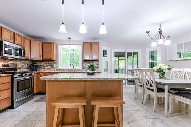kitchen with appliances with stainless steel finishes, tasteful backsplash, healthy amount of natural light, and brown cabinetry