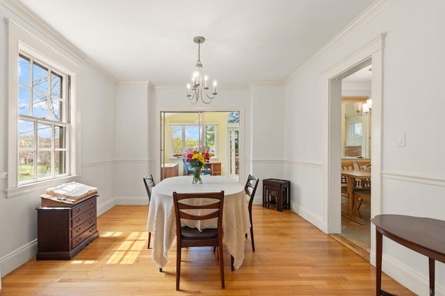 dining room with crown molding, a wealth of natural light, light wood finished floors, and a chandelier
