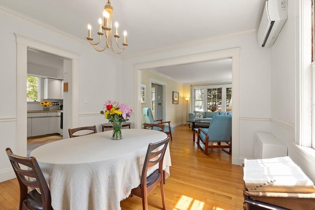 dining room with ornamental molding, a wall mounted AC, light wood-style flooring, and a notable chandelier