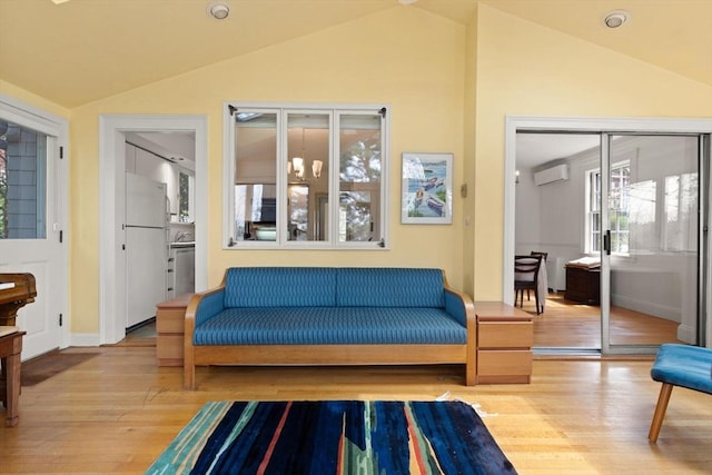 living area with baseboards, a wall mounted AC, lofted ceiling, and hardwood / wood-style flooring