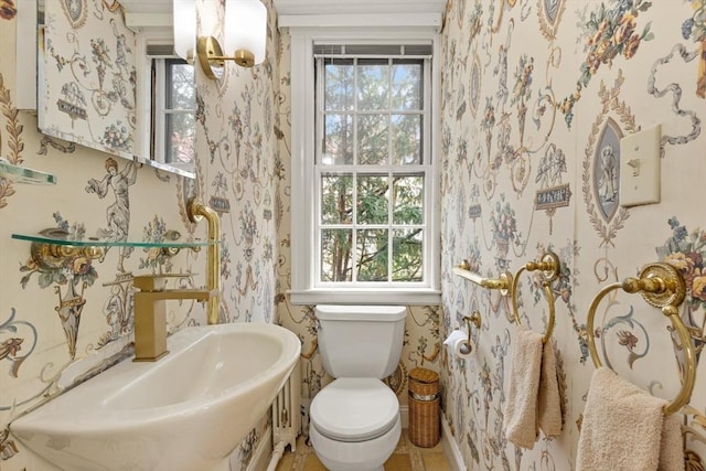 bathroom featuring a healthy amount of sunlight, toilet, and wallpapered walls