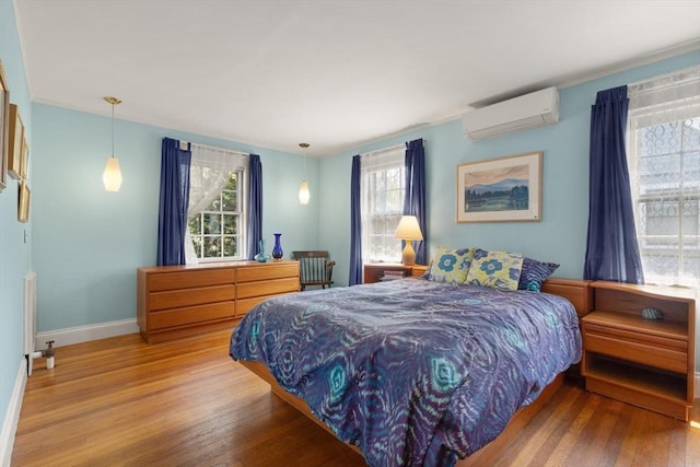 bedroom with baseboards, wood finished floors, and a wall mounted air conditioner