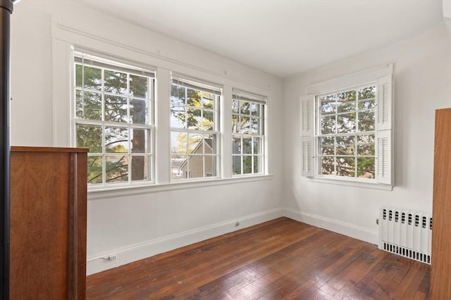 unfurnished room with baseboards, radiator, and hardwood / wood-style flooring
