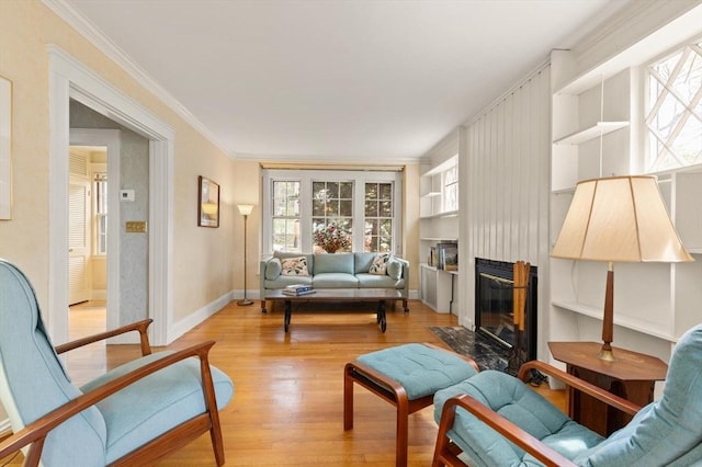 sitting room featuring ornamental molding, light wood-style flooring, and a high end fireplace