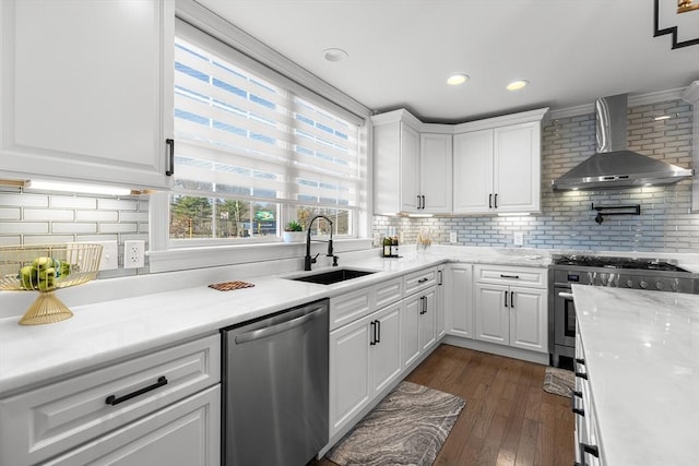 kitchen featuring dark wood-type flooring, a sink, appliances with stainless steel finishes, white cabinets, and wall chimney range hood