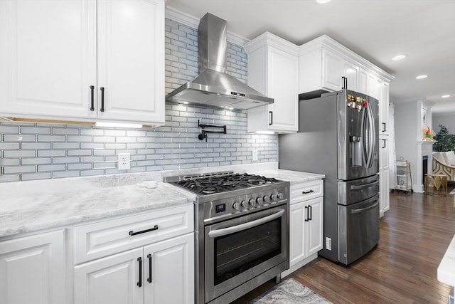 kitchen featuring decorative backsplash, wall chimney exhaust hood, white cabinetry, and appliances with stainless steel finishes