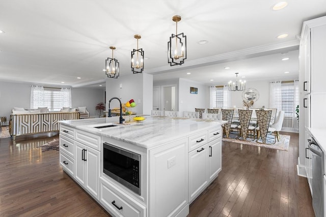 kitchen with a sink, an island with sink, stainless steel appliances, white cabinetry, and dark wood-style flooring