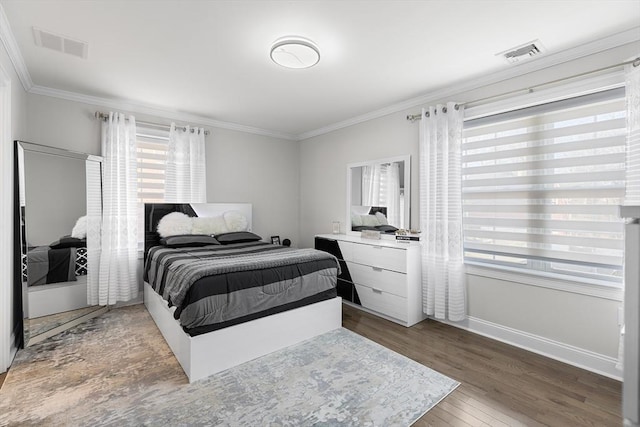 bedroom with visible vents, ornamental molding, baseboards, and wood finished floors