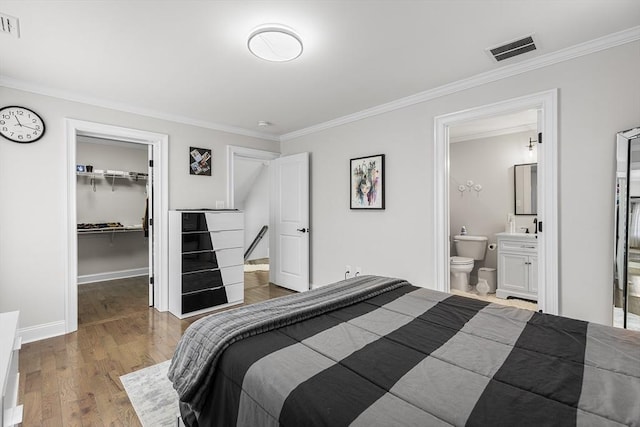 bedroom with visible vents, wood finished floors, a spacious closet, and crown molding