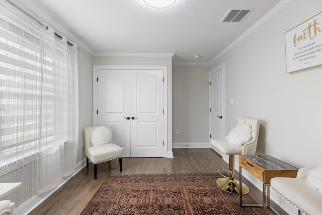 living area with visible vents, baseboards, wood finished floors, and ornamental molding