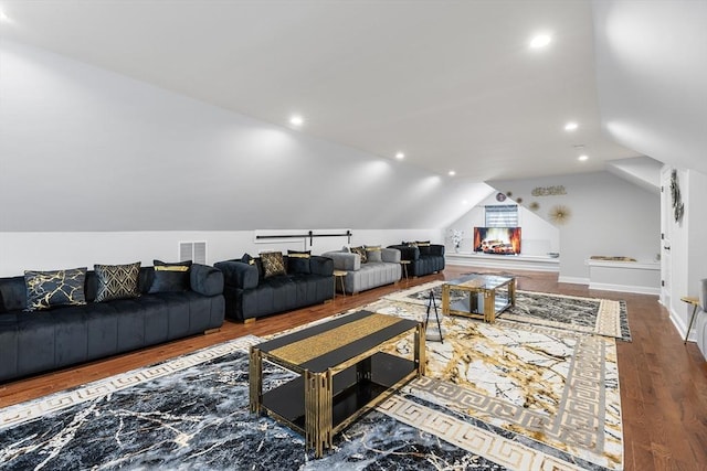 living area with lofted ceiling, recessed lighting, wood finished floors, and visible vents