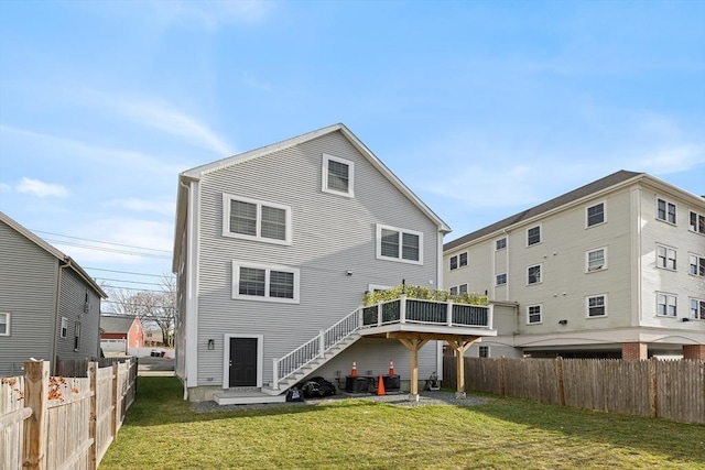 rear view of property with a lawn, stairs, and fence