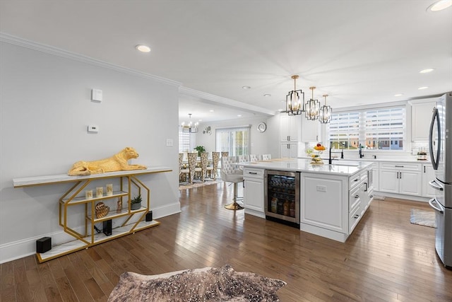 kitchen with beverage cooler, ornamental molding, hardwood / wood-style flooring, white cabinets, and a chandelier