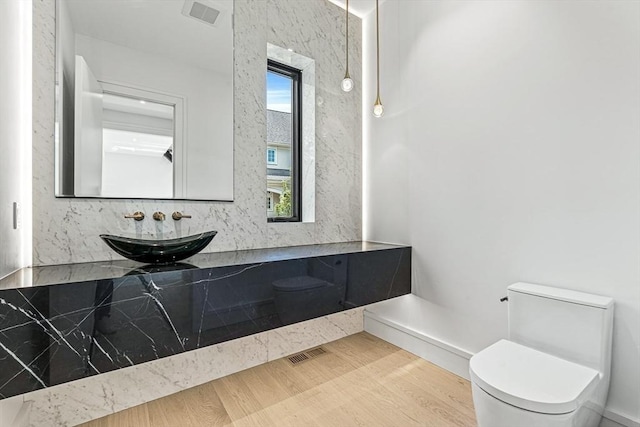 bathroom featuring visible vents, wood finished floors, a sink, and toilet