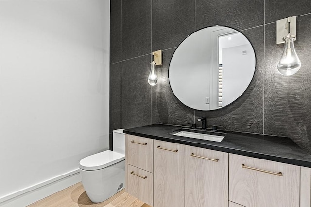 bathroom featuring wood finished floors, vanity, toilet, and decorative backsplash