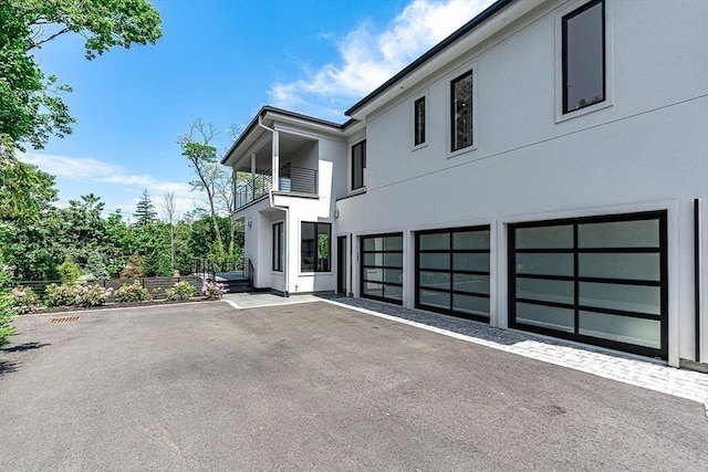 exterior space featuring a balcony, an attached garage, and stucco siding