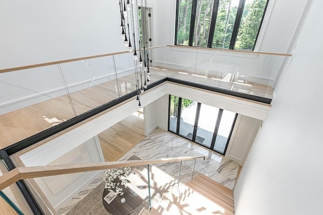 stairway featuring marble finish floor, a high ceiling, and a healthy amount of sunlight