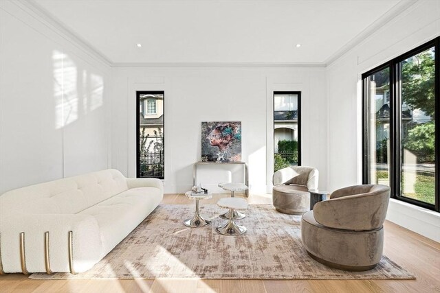 living area featuring a healthy amount of sunlight, crown molding, and wood finished floors