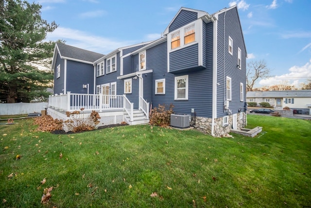 rear view of property with a lawn, cooling unit, and a deck