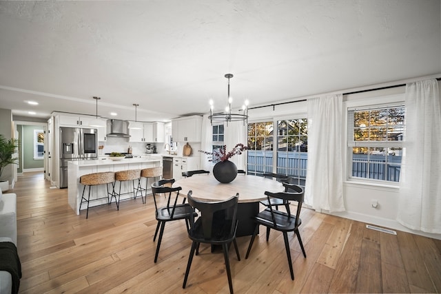 dining room with light hardwood / wood-style flooring, a notable chandelier, and sink