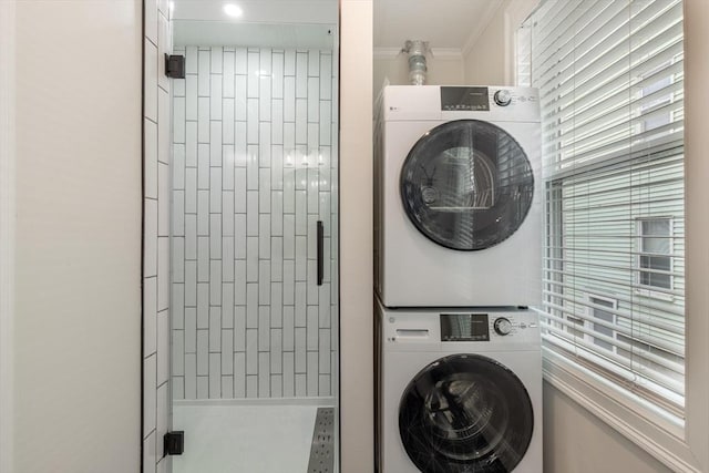 washroom featuring laundry area, crown molding, and stacked washer / dryer