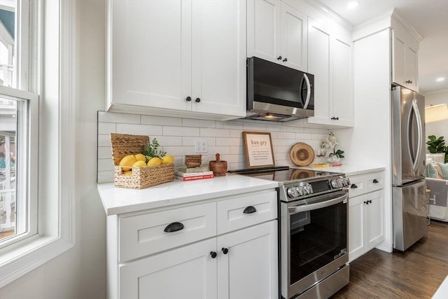 kitchen with stainless steel appliances, light countertops, decorative backsplash, and white cabinetry