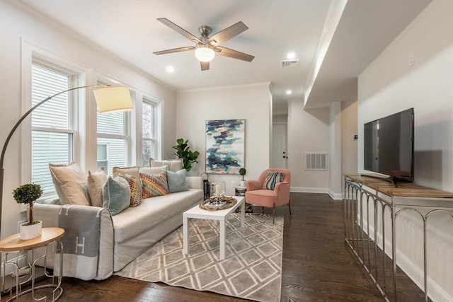 living area with crown molding, visible vents, and wood finished floors