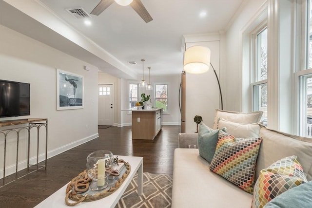 living room featuring dark wood-style flooring, visible vents, crown molding, and baseboards