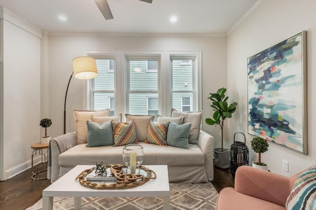 living area featuring dark wood-type flooring, crown molding, baseboards, and ceiling fan