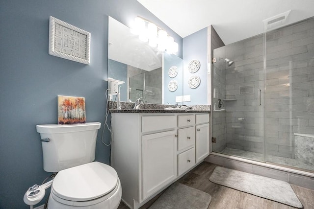 bathroom featuring a shower stall, wood finished floors, toilet, and vanity