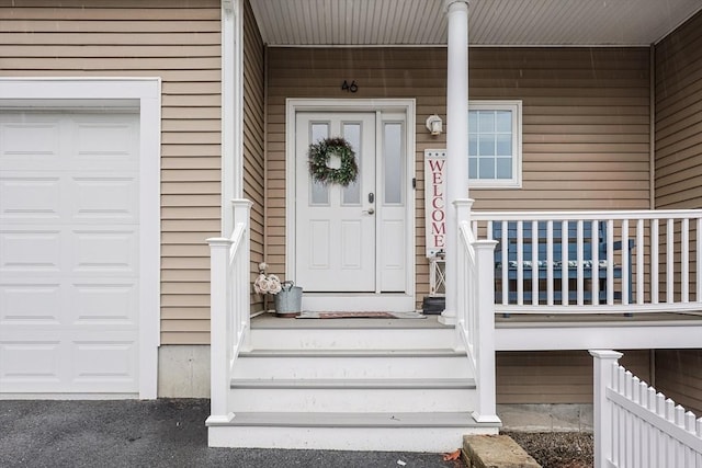 view of exterior entry featuring a porch and a garage
